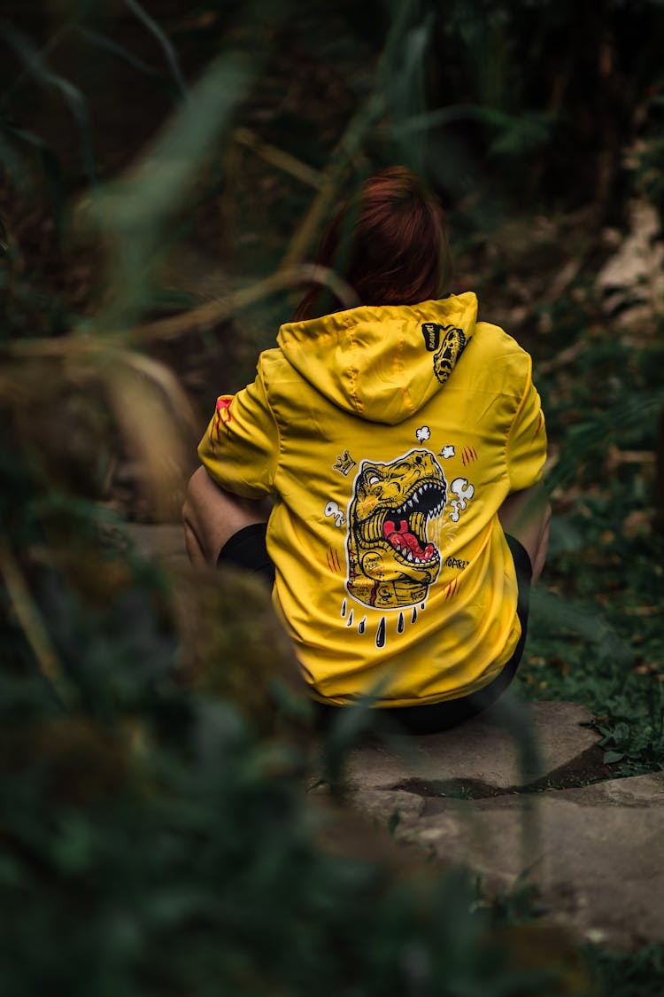 Back View Of A Woman In A Yellow Hoodie Sitting