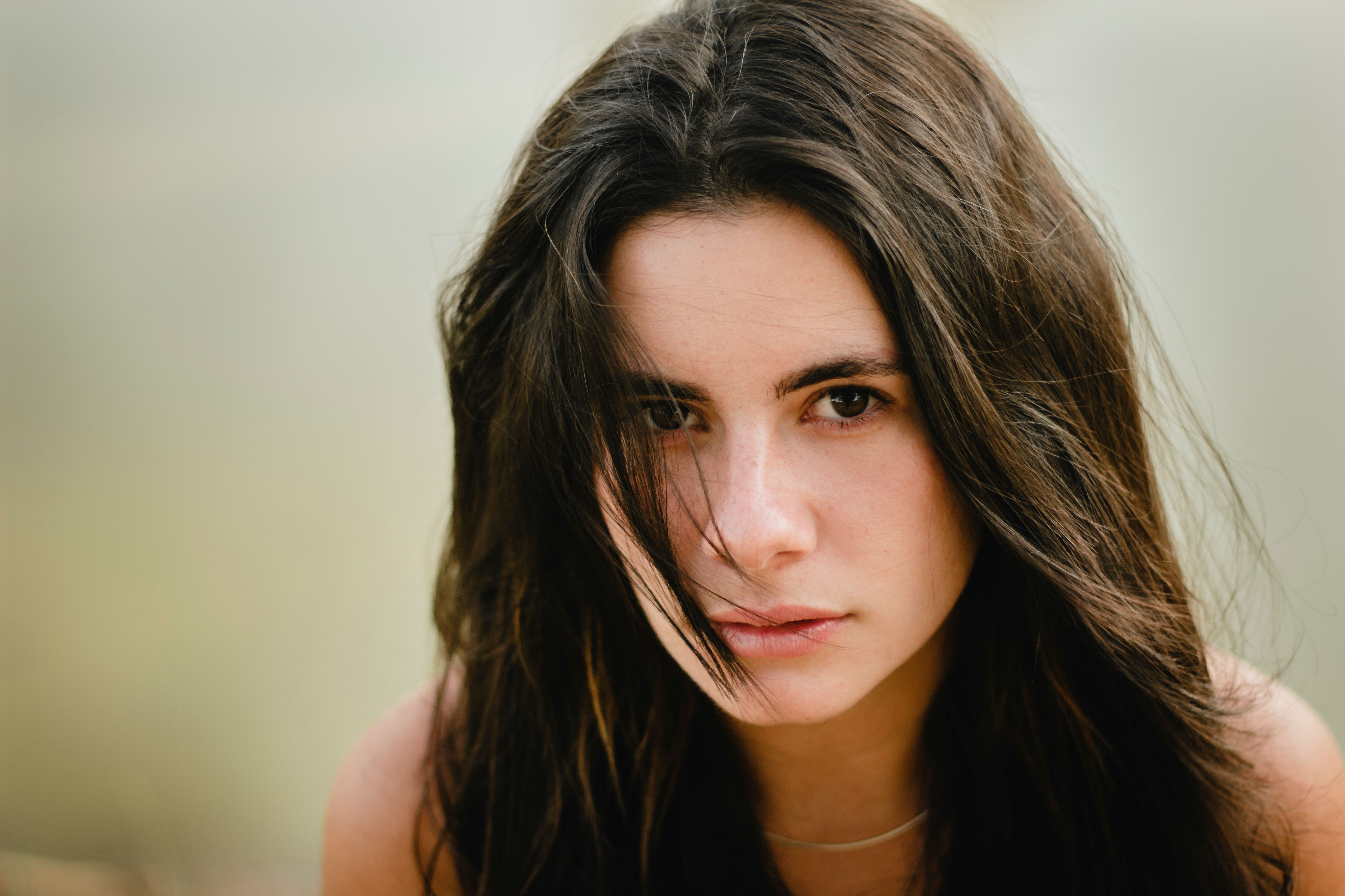 Close-up portrait of a young woman with long hair looking serene outdoors.