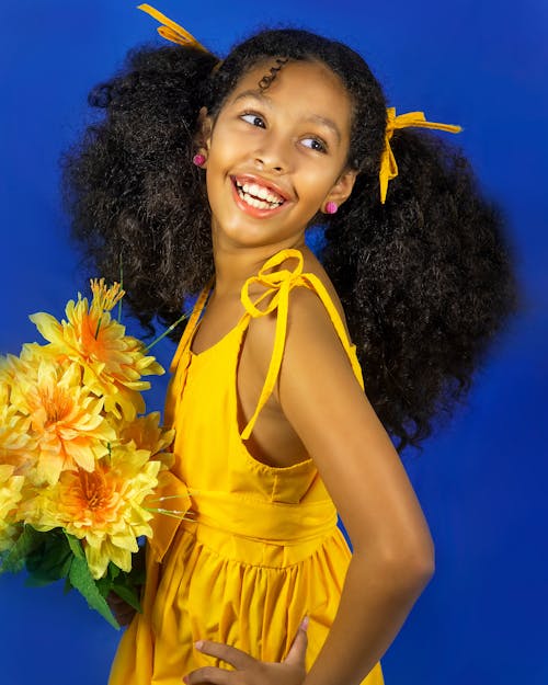 Studio Portrait of a Little Girl Posing with Yellow Flowers in Hand