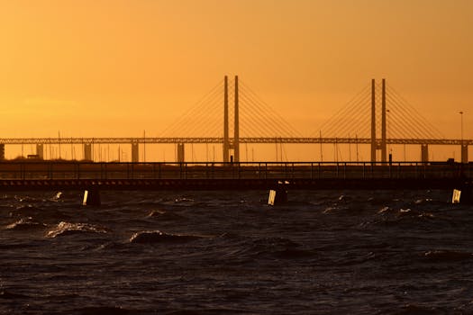 Stunning sunset over the Öresund Bridge in Malmö, Sweden, with vibrant orange sky.