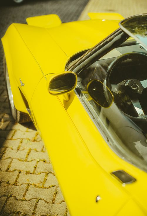 Free Close-up view of a bright yellow vintage car parked outdoors on a sunny day. Stock Photo