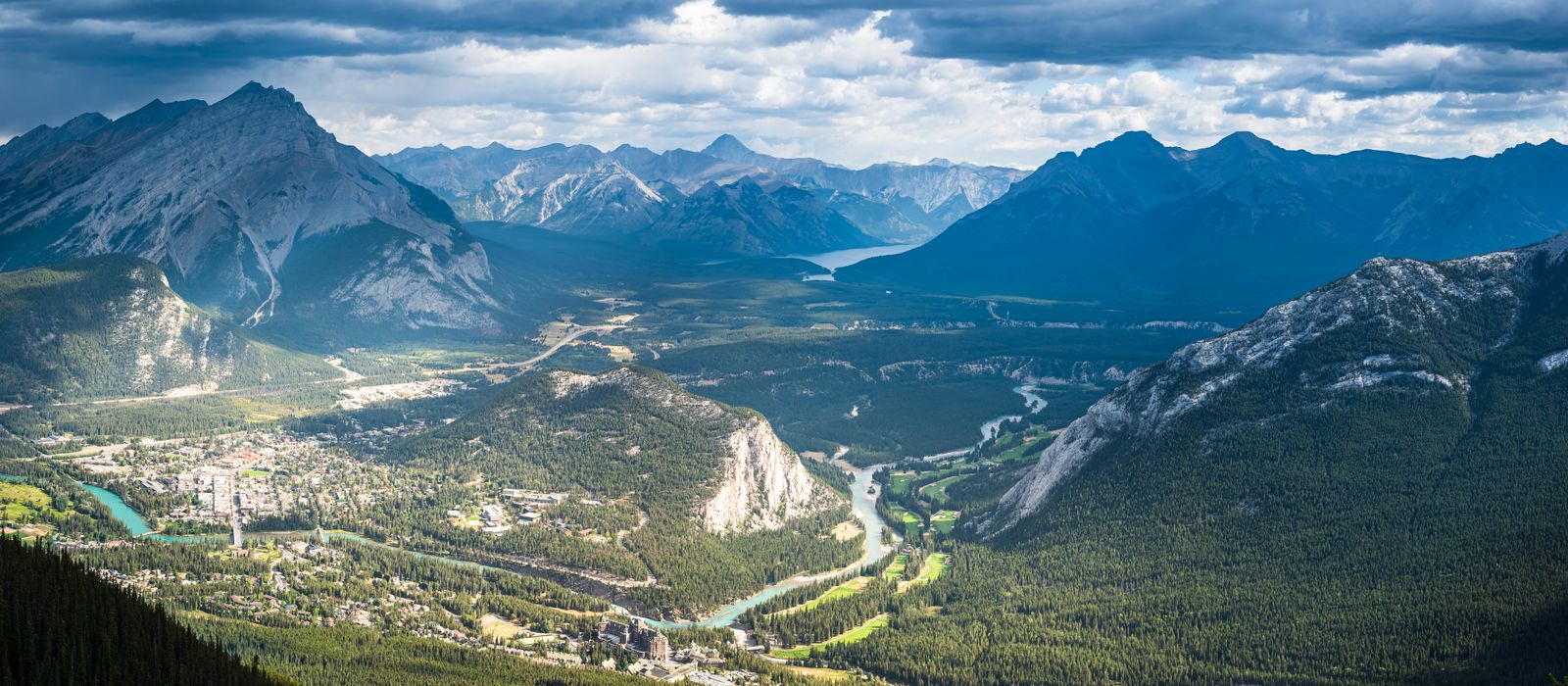Scenic vista of cloud-covered mountain peaks and lush valleys in Banff National Park.
