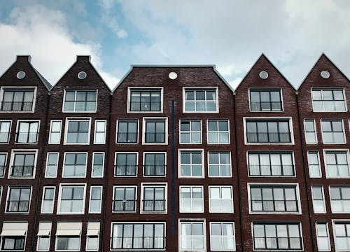 Brick Building Apartments with Glass Windows Under a Cloudy Sky