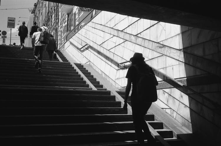 Grayscale Photo Of People Walking Up The Stairs