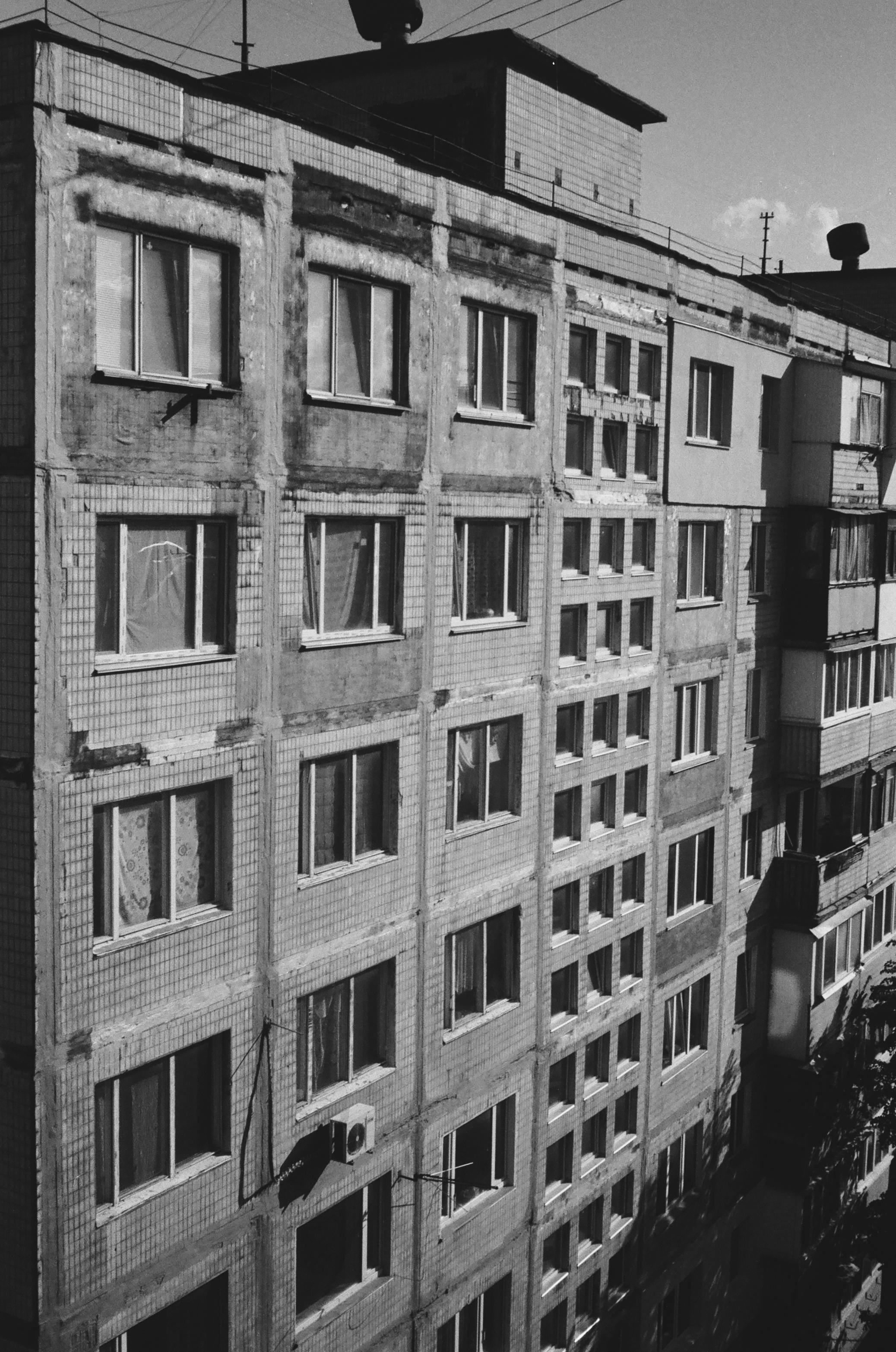 Monochrome photograph of a Soviet-era apartment building facade in Kyiv, Ukraine.