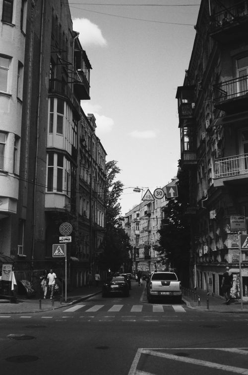 Free Black and white scene of a street in Kyiv, featuring historic architecture and vehicles. Stock Photo