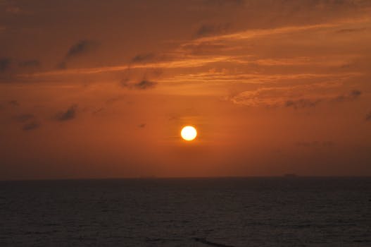 A breathtaking view of the sunset over the ocean, with a brilliantly orange sky and serene sea below.