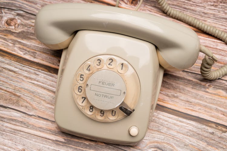 White Rotary Phone On Brown Wooden Table