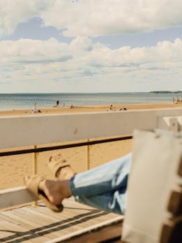 A serene beach scene with people relaxing, viewed from a wooden deck.