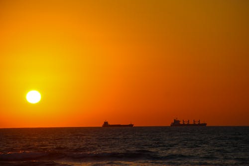Silhouettes of Ships at Sea During Sunset