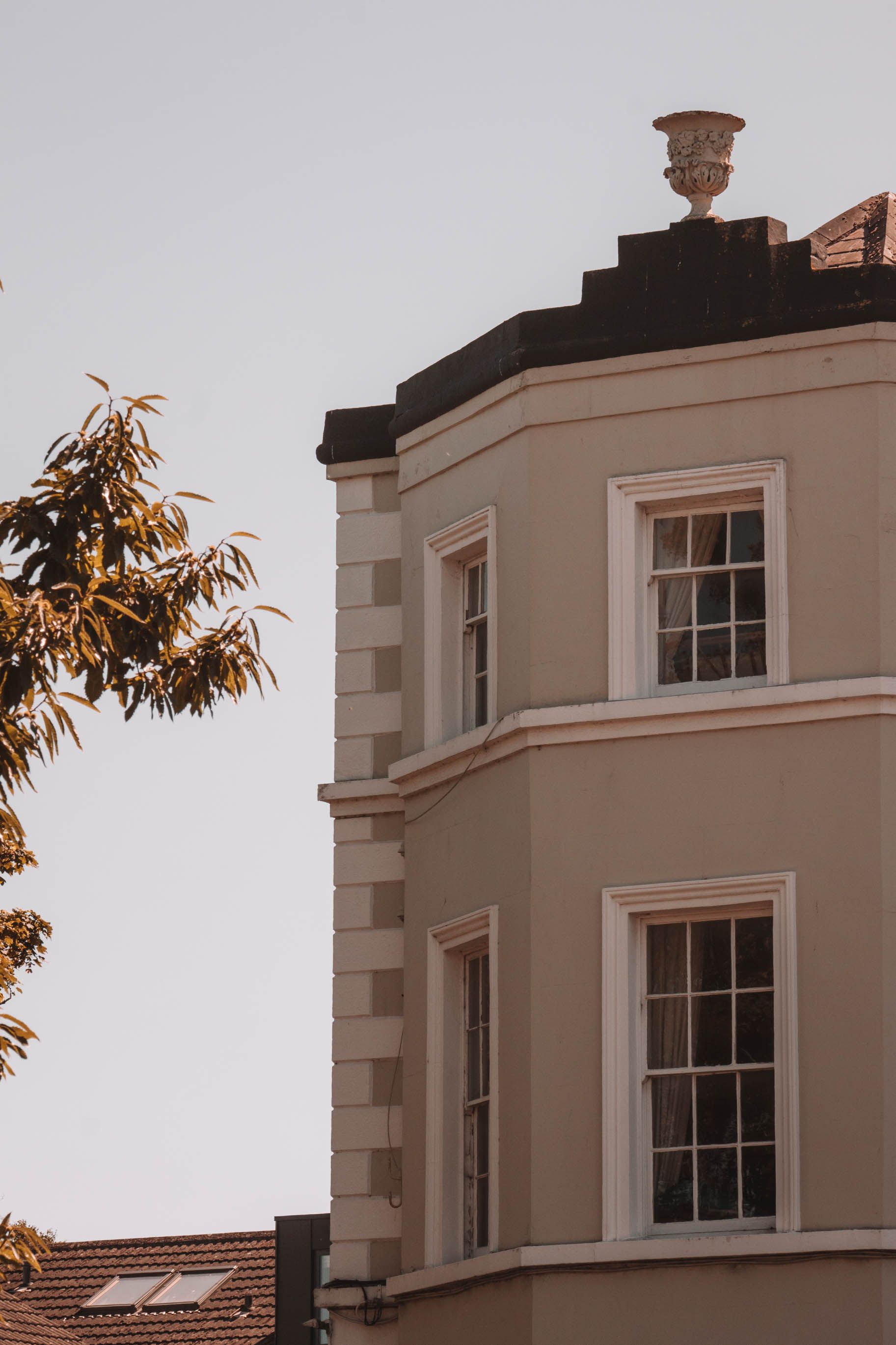 Elegant residential building exterior with windows, featuring a decorative urn on the rooftop.