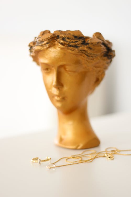 A Gold Necklace Near a Head Figurine