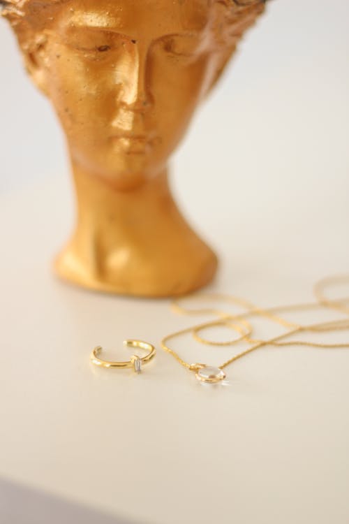 A Ring and Necklace Near a Head Figurine