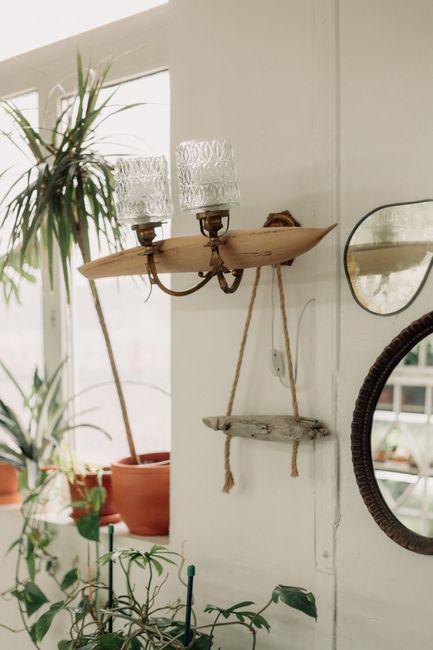 Cozy indoor setting featuring antique lamps, potted plants, and mirrors on a sunlit wall.