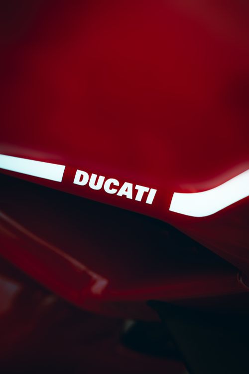 Free Close-up image of a red motorcycle featuring Ducati branding on a smooth surface. Stock Photo