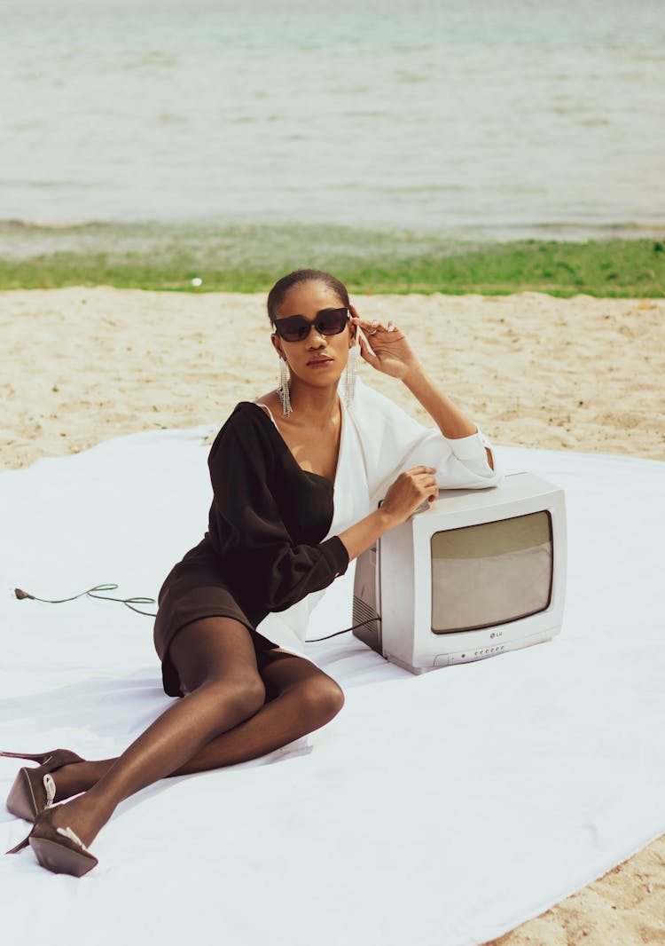 Woman Posing On A Blanket At The Beach Leaning On An Old TV