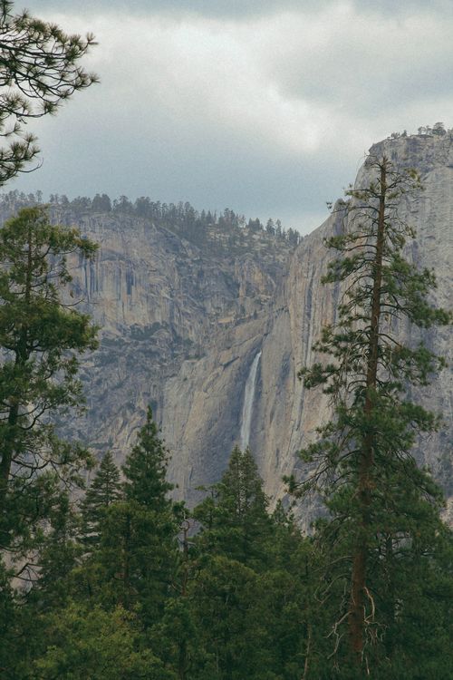 Free Breathtaking view of a waterfall cascading down cliffs in Yosemite, amid lush forests. Stock Photo