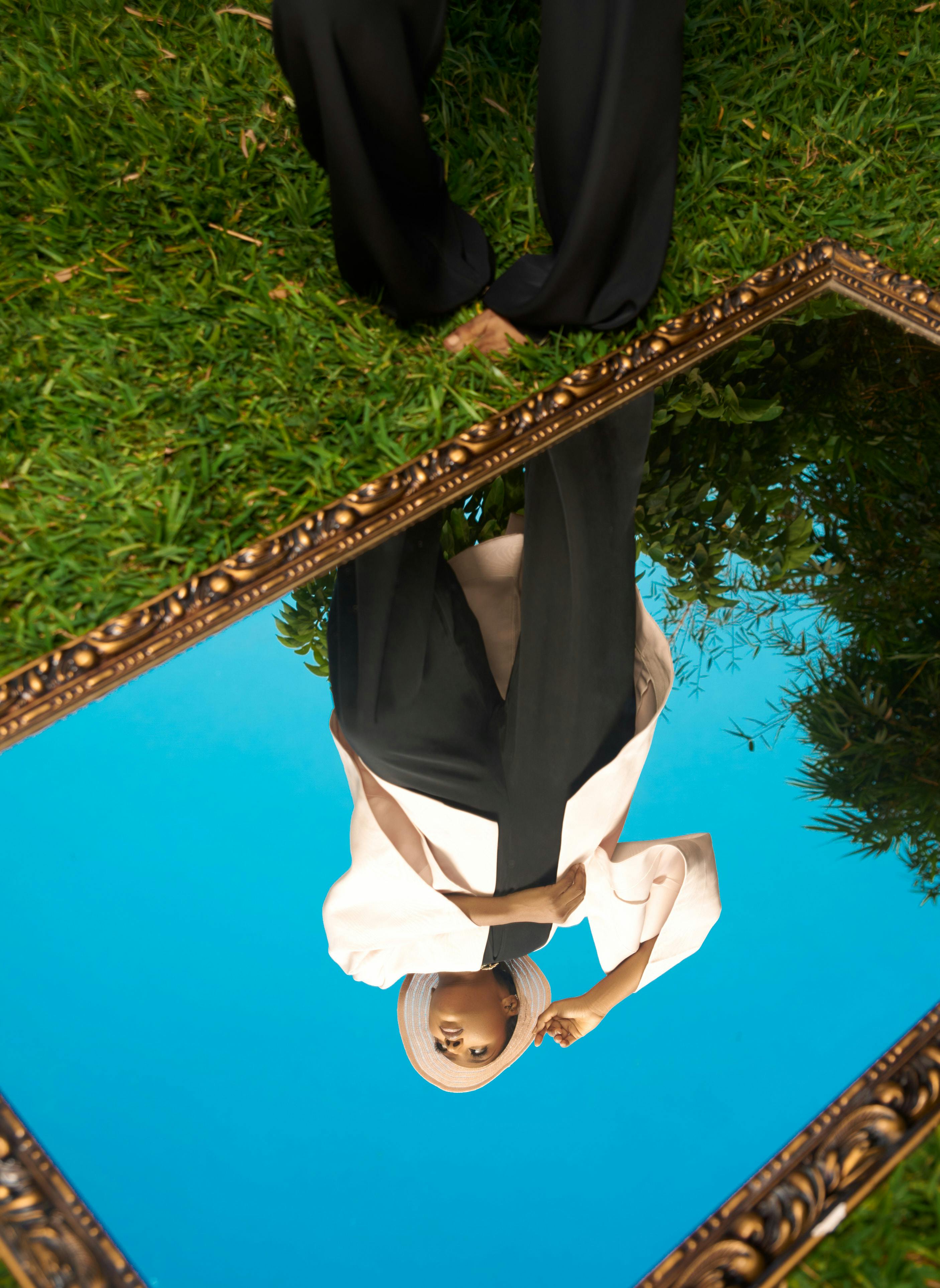 Free Artistic photo of a woman in a hijab reflecting in a mirror on grass. Stock Photo
