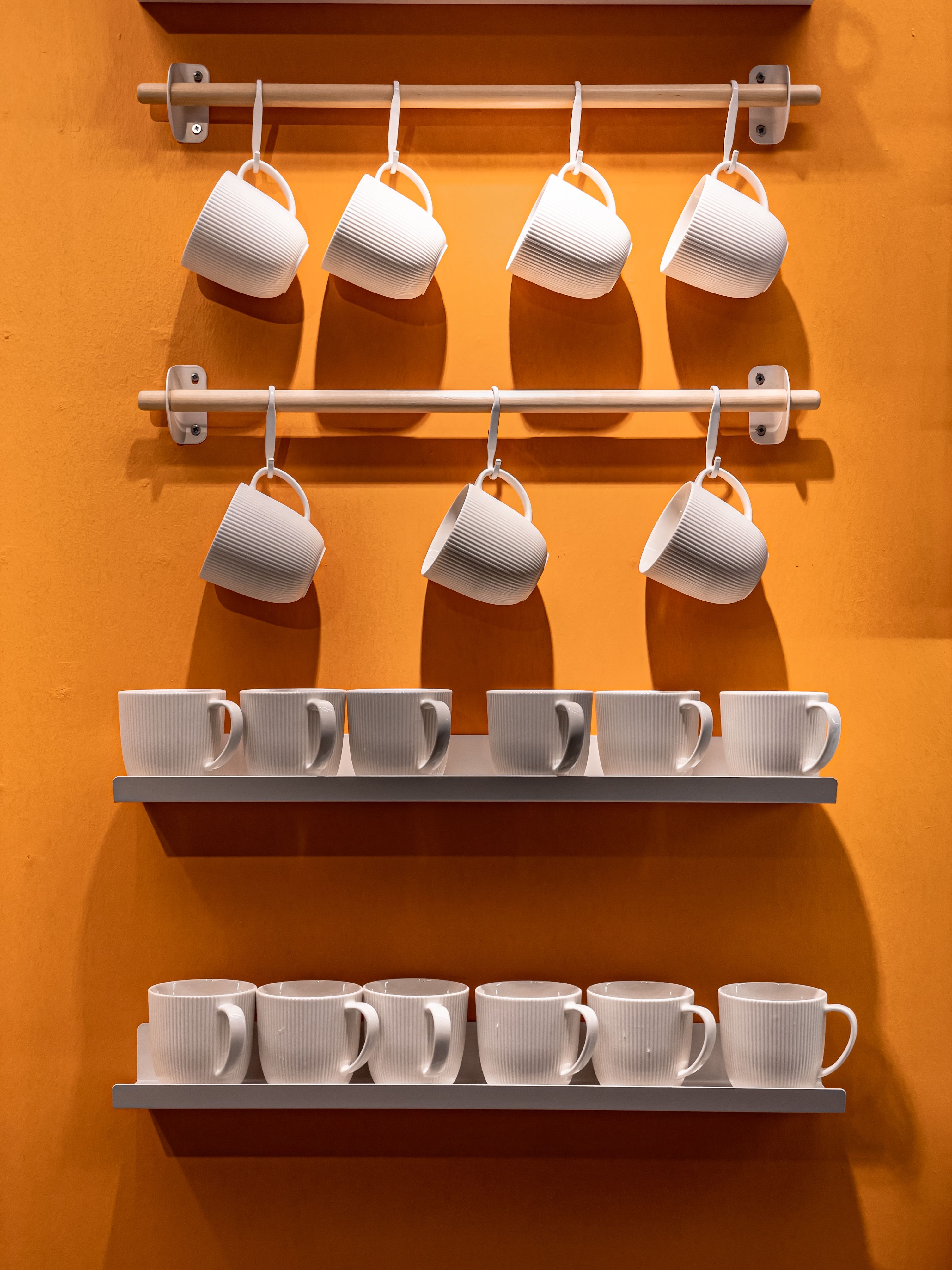 white floating shelves above a coffee bar holding colorful ceramic coffee mugs