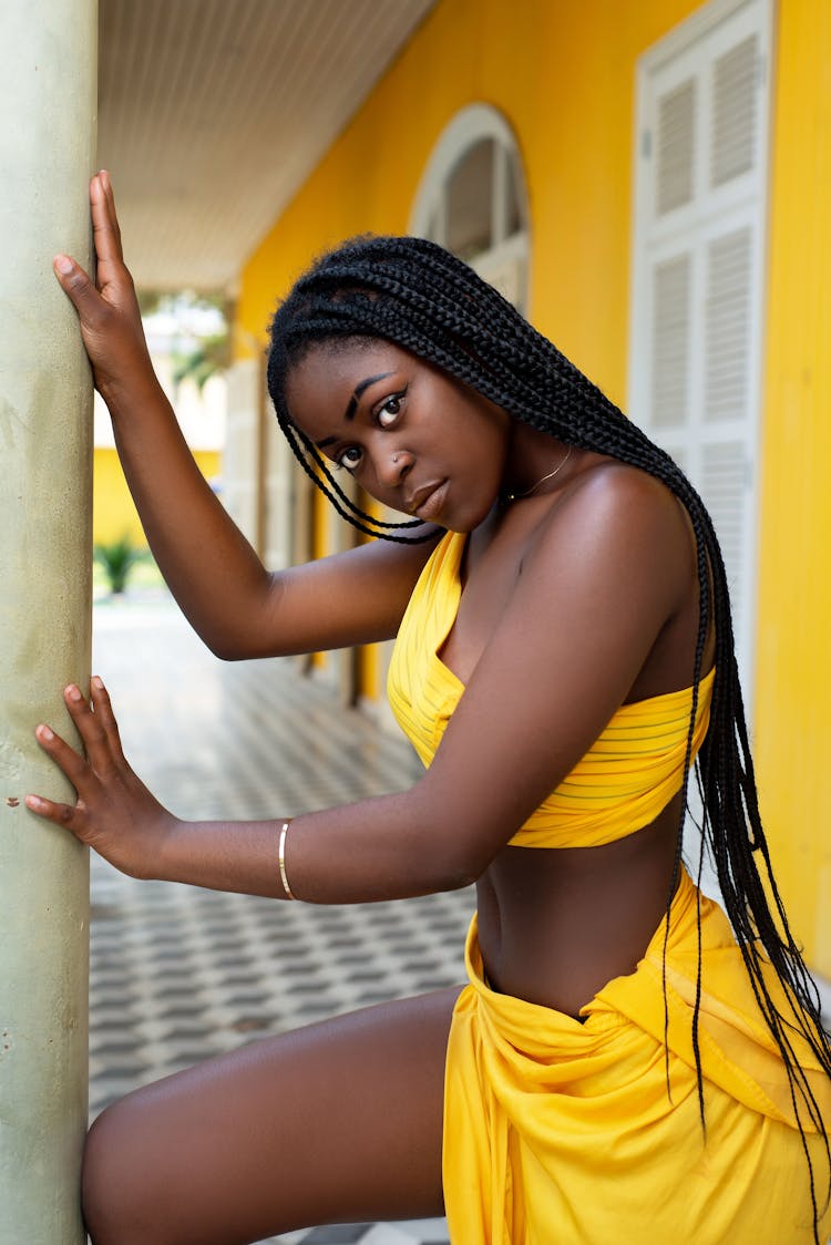 Woman In Yellow Outfit Against A Yellow Wall 