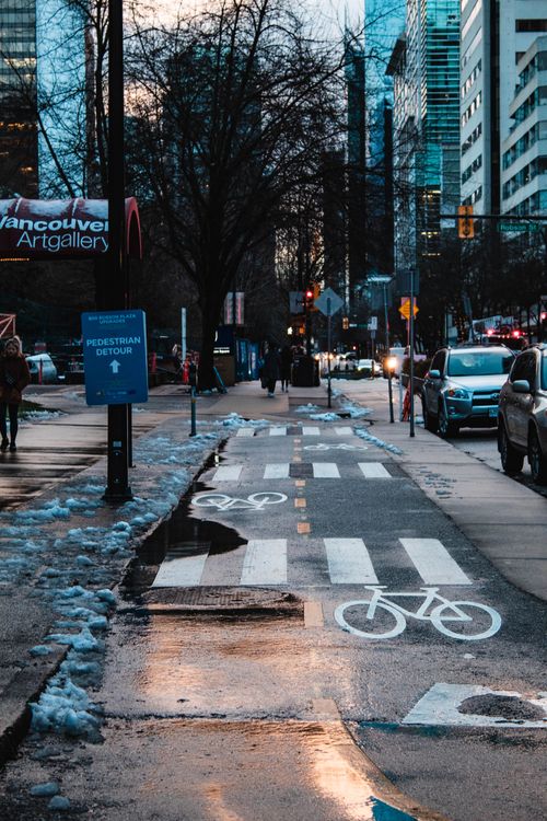 Free Vancouver street with wet pavement and bike lane at dusk. Stock Photo