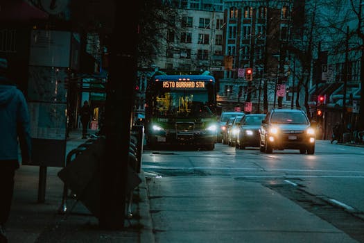 City street at night featuring a bus heading to Burrard Station with urban buildings in the background.