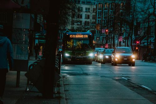 Free City street at night featuring a bus heading to Burrard Station with urban buildings in the background. Stock Photo