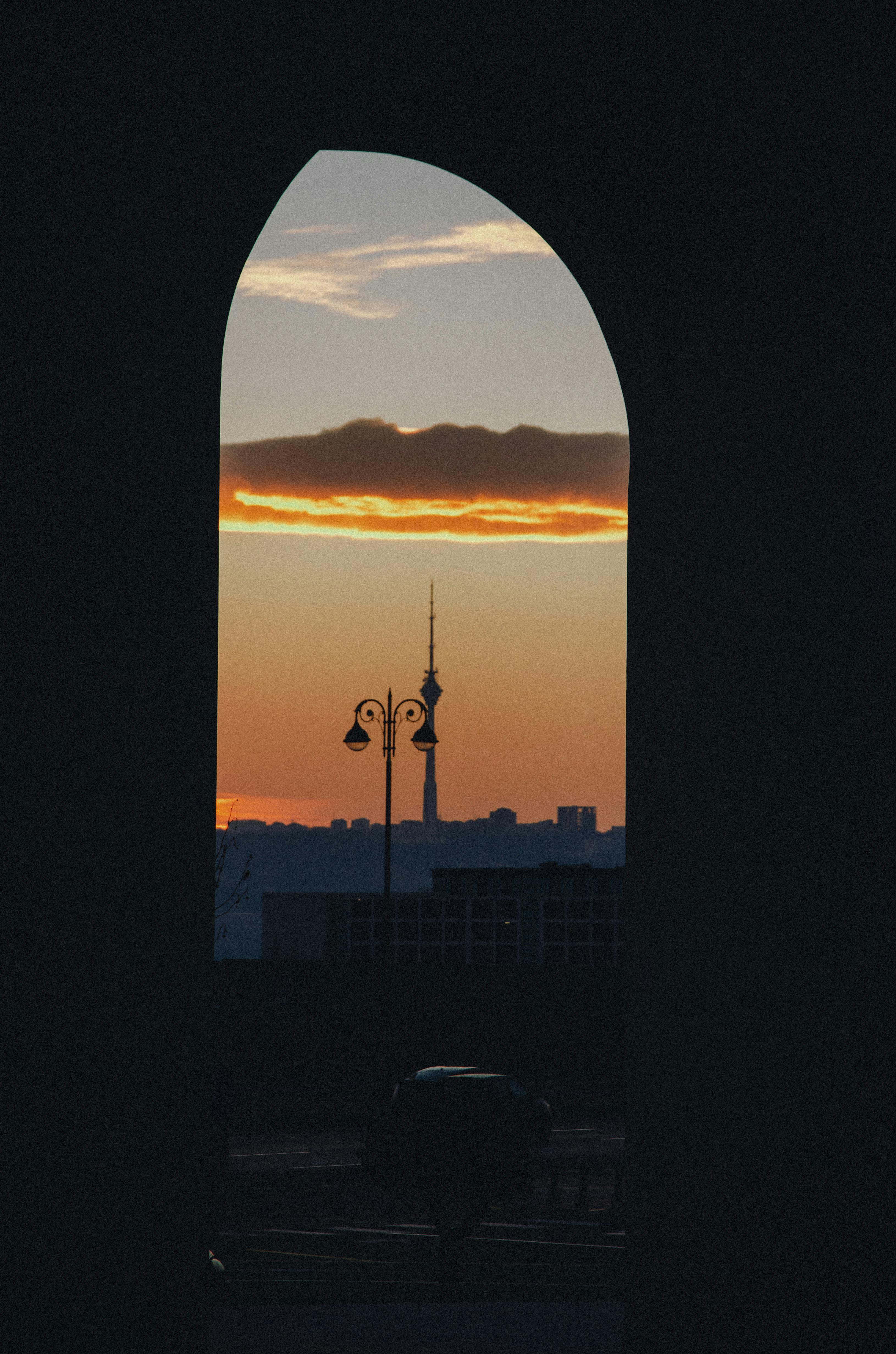 A stunning view of the Baku TV Tower silhouetted against a vibrant sunset through an archway.