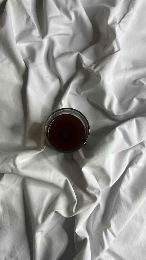 Free A minimalist top-down view of a coffee cup placed on crumpled white sheets, ideal for lifestyle concepts. Stock Photo