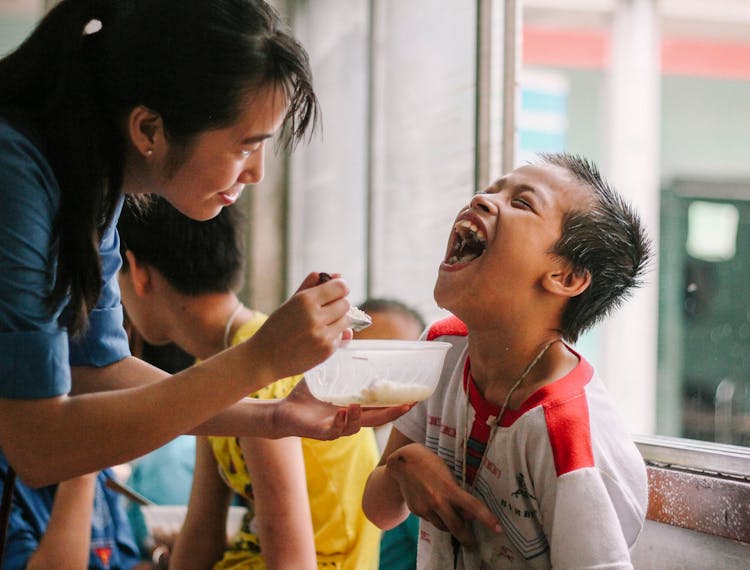 Woman Feeding A Boy