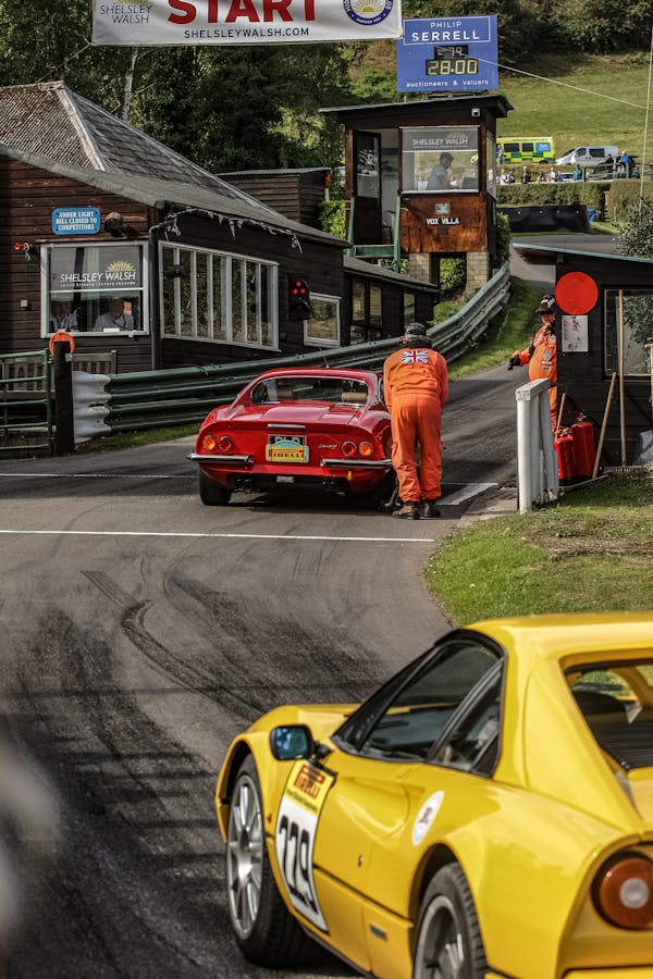 Yellow and Red Car on a Racing Track an Men Wearing Orange Uniforms