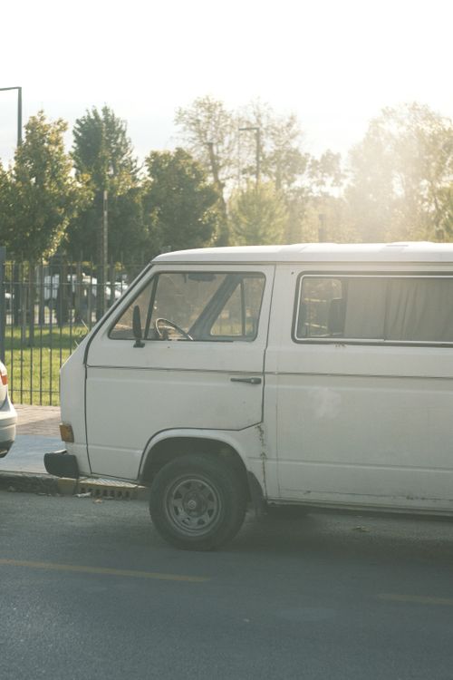 Free Old white van parked by the curb on a sunny street, exuding a nostalgic and serene vibe. Stock Photo