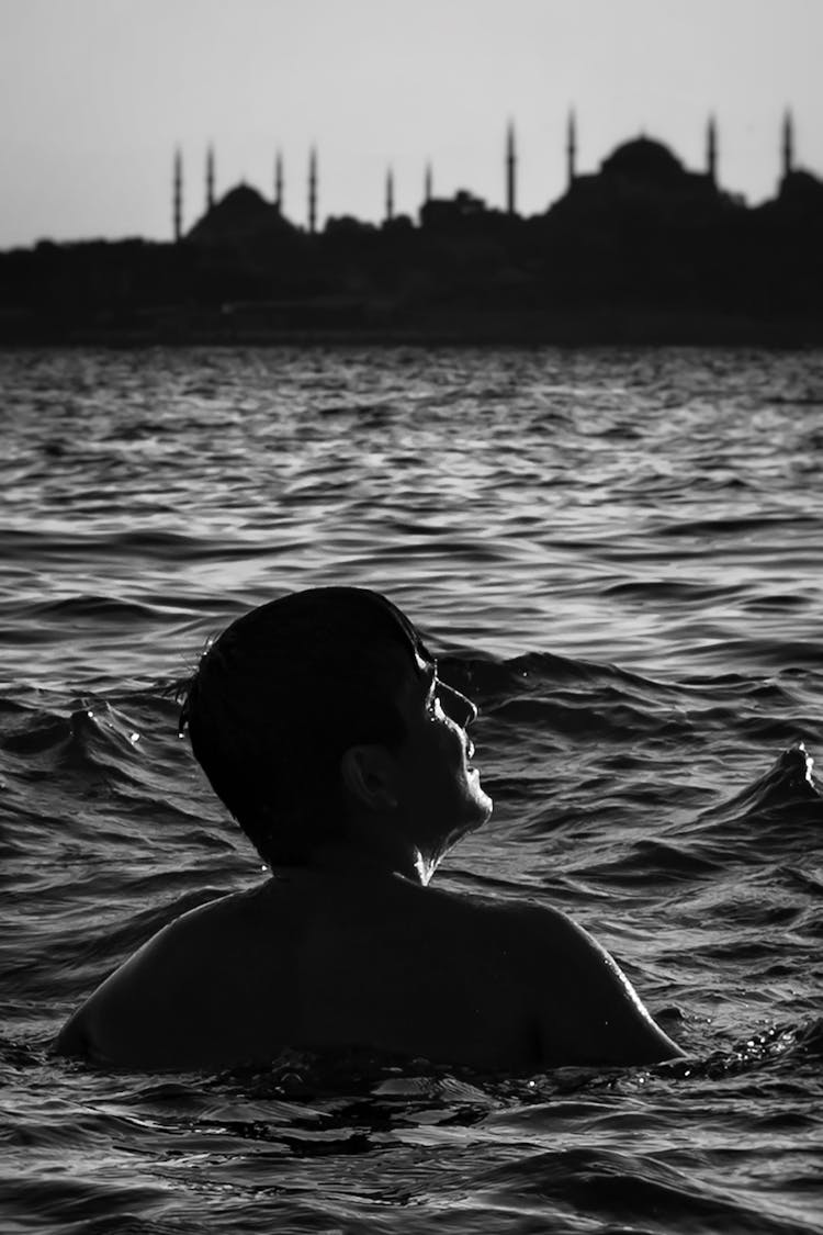 Grayscale Photo Of A Man Swimming In The Ocean