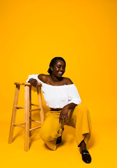 Gratis lagerfoto af afroamerikansk kvinde, crouching, gul baggrund