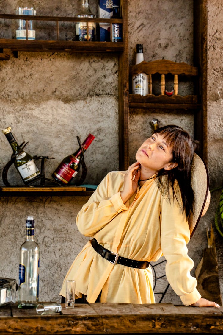 Woman Standing Behind A Ranch Bar With Liquor Bottles Behind Her 