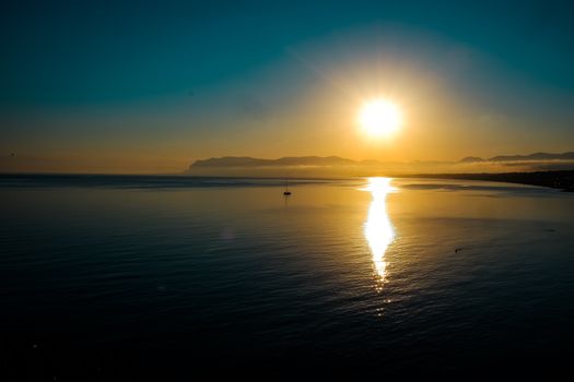 Serene sunrise view over Castellammare del Golfo, Sicily, with calm sea and scenic coastline.