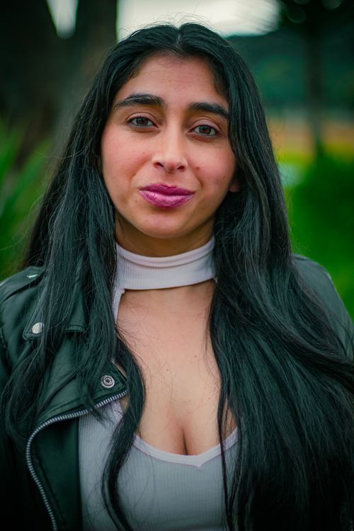 Free Close-up portrait of a young woman outdoors in a leather jacket with long dark hair and a calm expression. Stock Photo