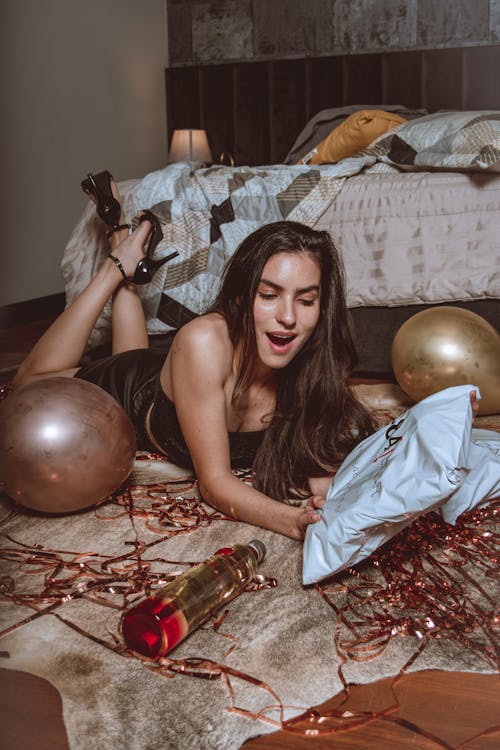 Free Woman Lying Down on the Carpet Holding a Package Stock Photo