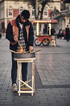 A street vendor in traditional attire preparing food in a busy urban street setting.