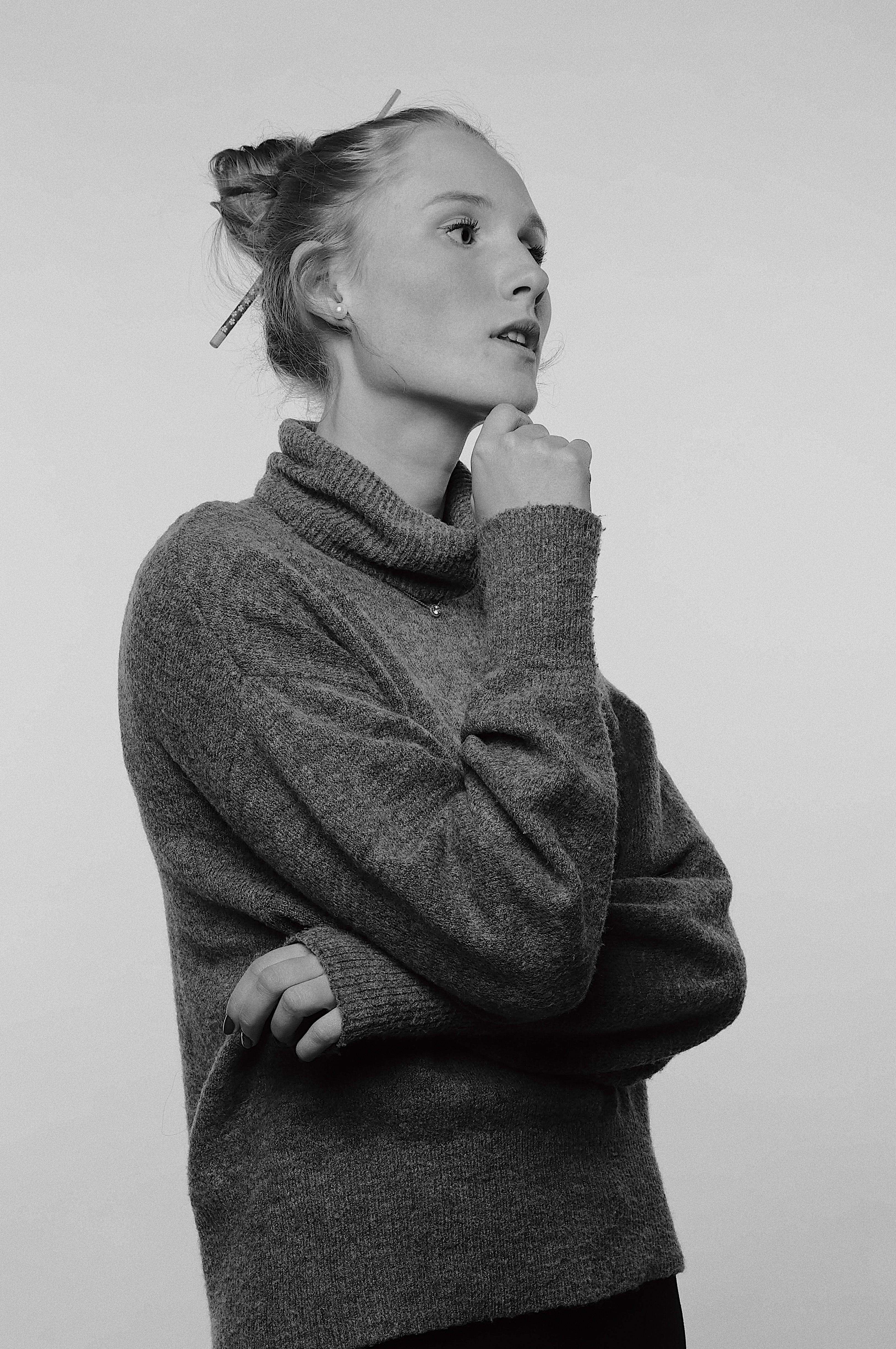 A grayscale portrait of a young woman in a gray sweater, looking thoughtful and poised.