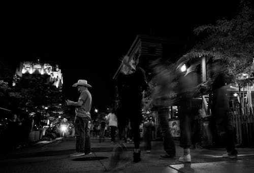 Grayscale Photo of People Walking on the Street During Night Time