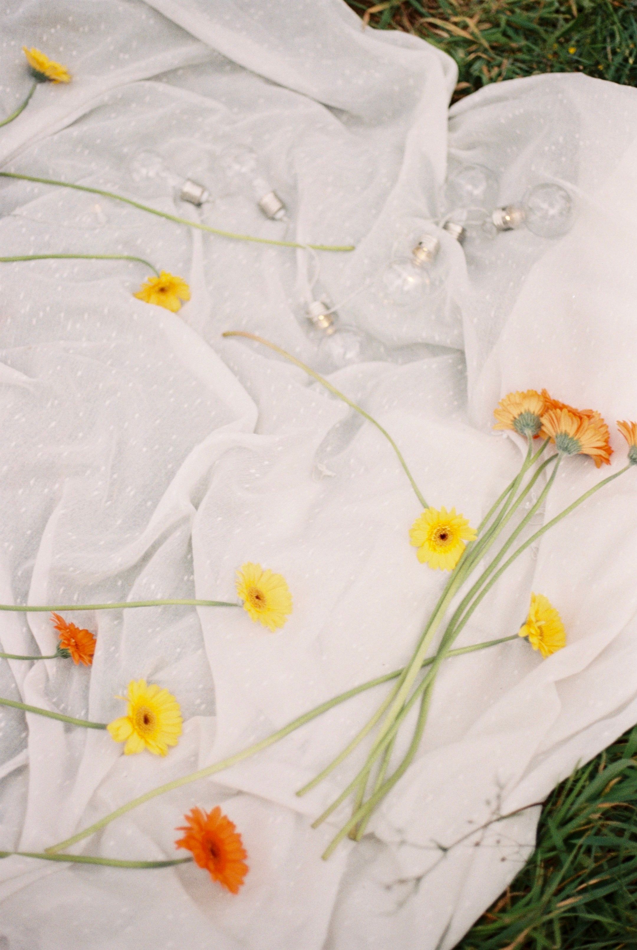 A flat lay of marigold flowers on a white cloth with light bulbs, evoking a serene mood.