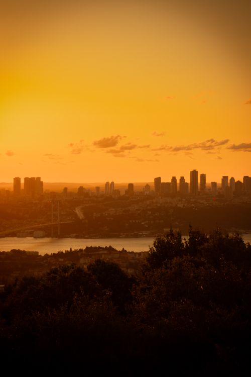 Free Silhouette of a city skyline at sunset with a vibrant orange sky. Stock Photo