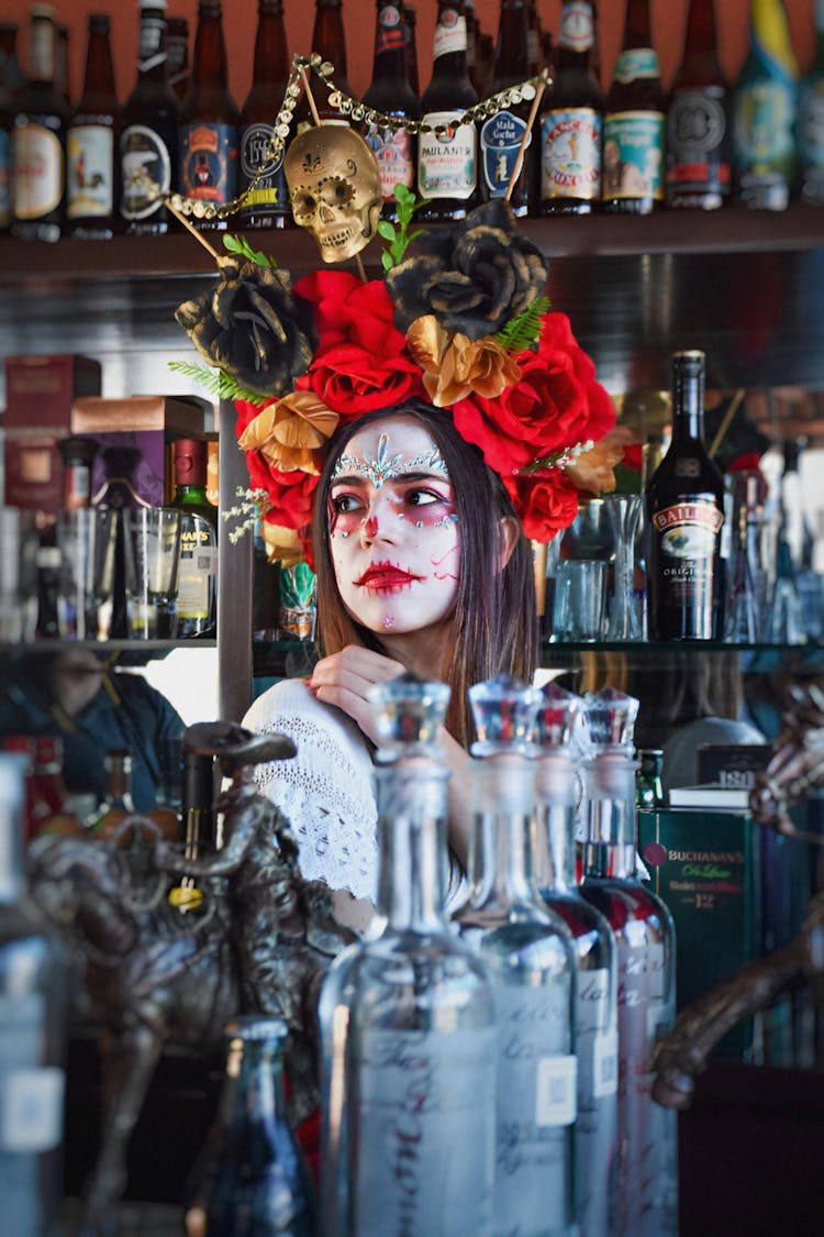 Woman In Makeup And A Headpiece Standing Behind A Counter In A Bar