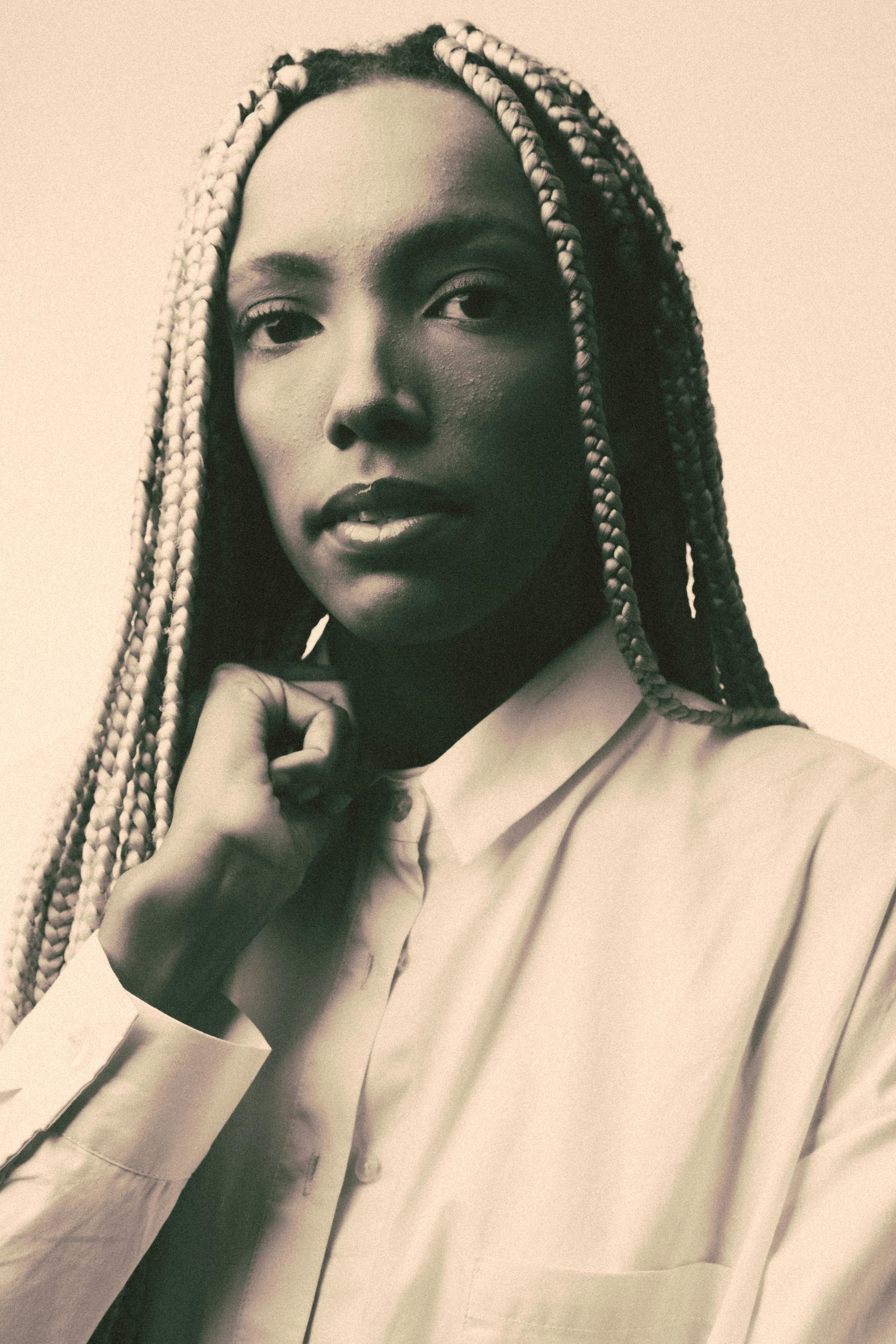 Sepia-toned portrait of a woman with braided hair, creating a stylish and mysterious look.