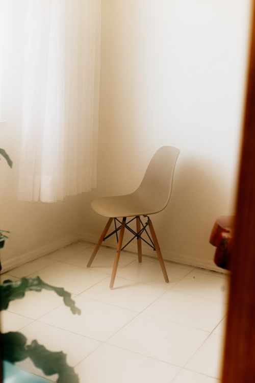 Free Modern minimalist corner with a wooden chair and white curtain in soft lighting. Stock Photo