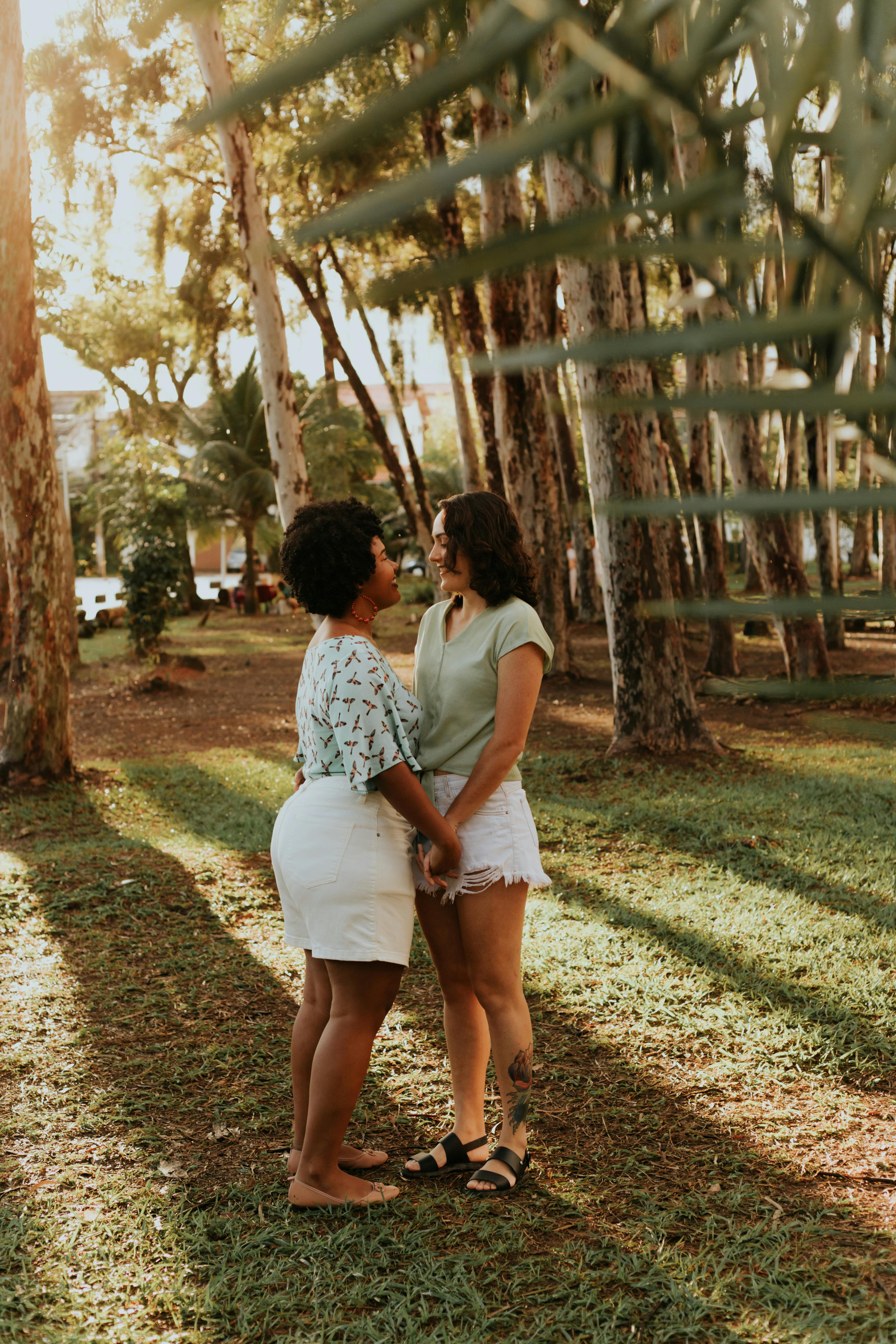 Two women holding hands in a sunlit Salvador park, enjoying a peaceful afternoon.