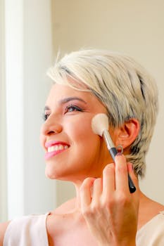 Portrait of a woman with short hair applying makeup with a brush.
