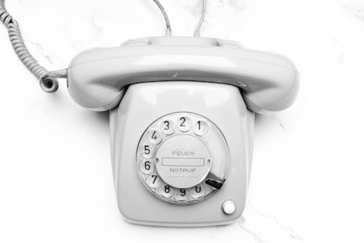Classic gray rotary phone on marble surface emphasizing retro style and nostalgia.