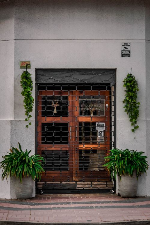 Free An inviting wooden entrance framed by lush green plants and vines, perfect for architectural themes. Stock Photo